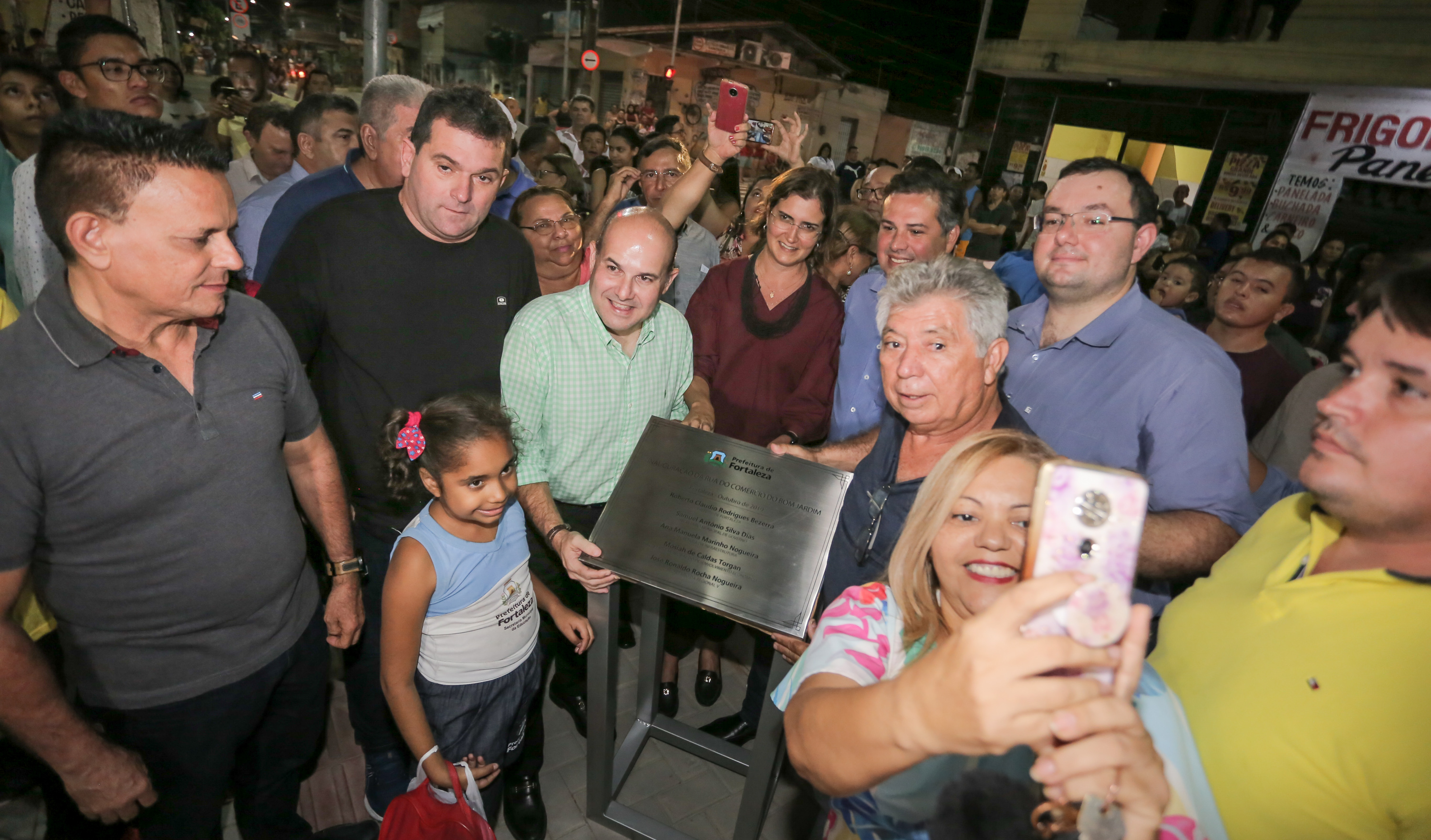 várias pessoas ao redor de uma placa de inauguração